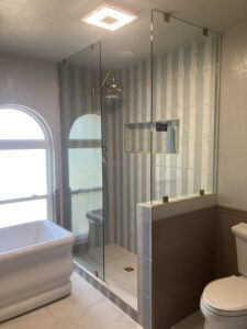 Beautiful renovated bathroom featuring a sleek glass shower, elegant tiles, and a cozy tub.