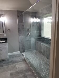 Stylish walk-in shower with gray tile walls and textured floor tiles in a contemporary bathroom.