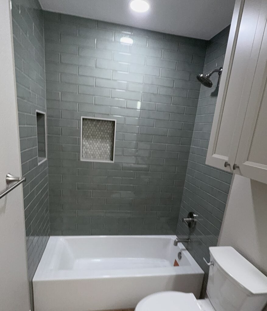 Bathroom remodel featuring gray subway tiles, built-in shower niches, and contemporary fixtures.