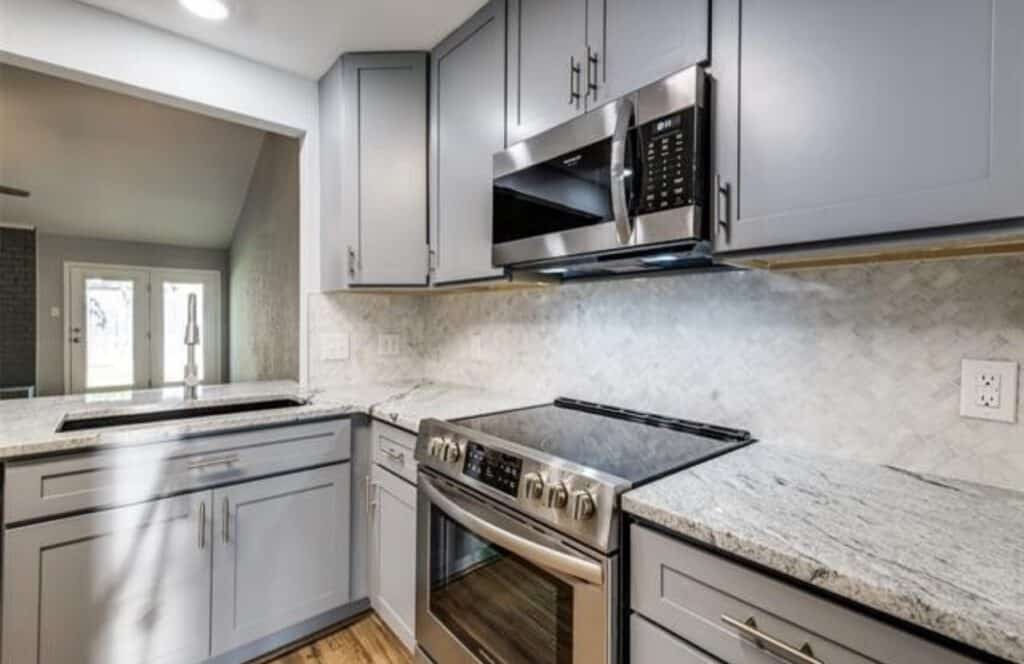 Spacious kitchen with sleek gray cabinetry, granite countertops, and modern stainless steel appliances.