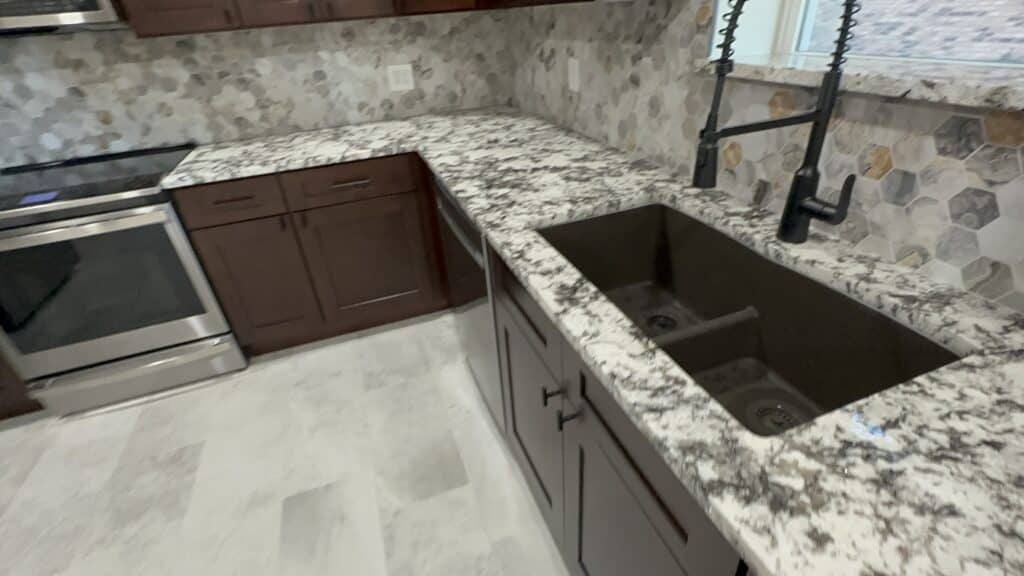 High-resolution image of a renovated kitchen featuring granite countertops, dark and light cabinets, and stylish backsplash tiles.
