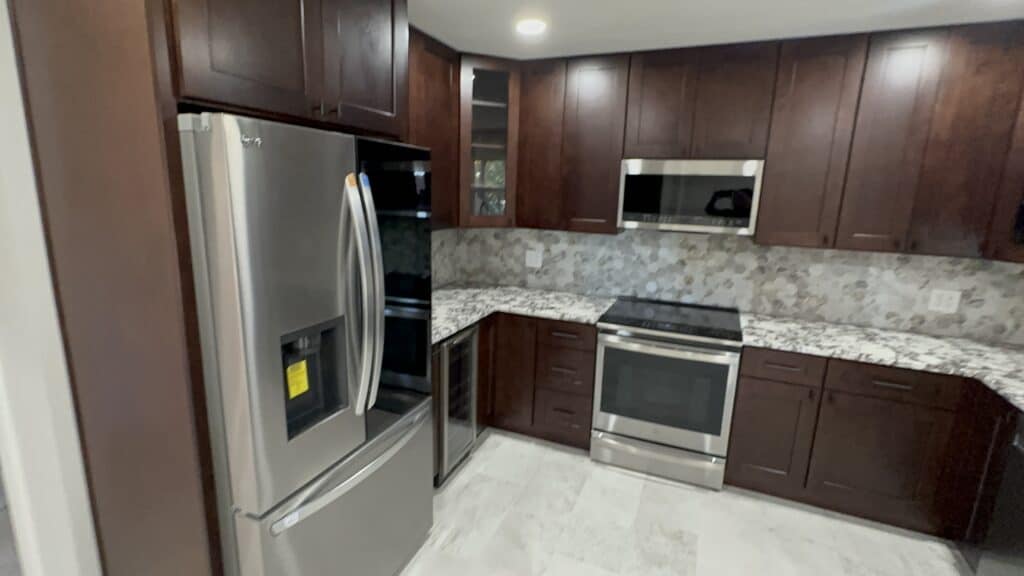 Beautiful kitchen renovation showcasing dark cabinetry, granite countertops, and stainless steel appliances for upscale home design.