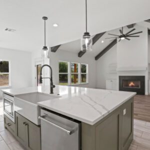 Modern kitchen with white cabinetry and marble countertops in a bright, open-concept living space.