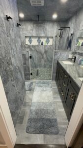 Remodeled bathroom showcasing contemporary gray marble tiles, a walk-in shower, and a spacious vanity for a fresh, updated look.