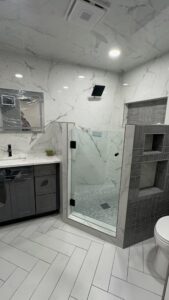 Luxurious bathroom remodel featuring marble walls, glass shower, and custom cabinetry.