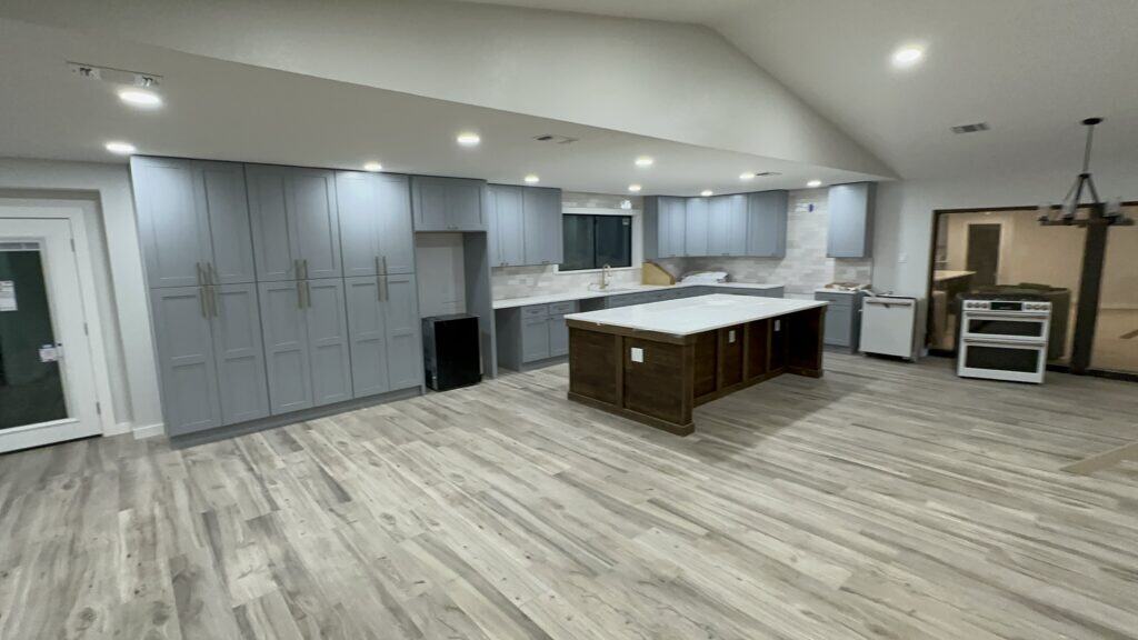 Spacious kitchen with gray cabinets, marble countertops, and new appliances for renovation projects.