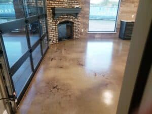 Durable, polished stained concrete floor in a modern kitchen remodel with rustic brick fireplace.