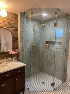 Beautiful walk-in glass shower with brass fixtures and tile accents.