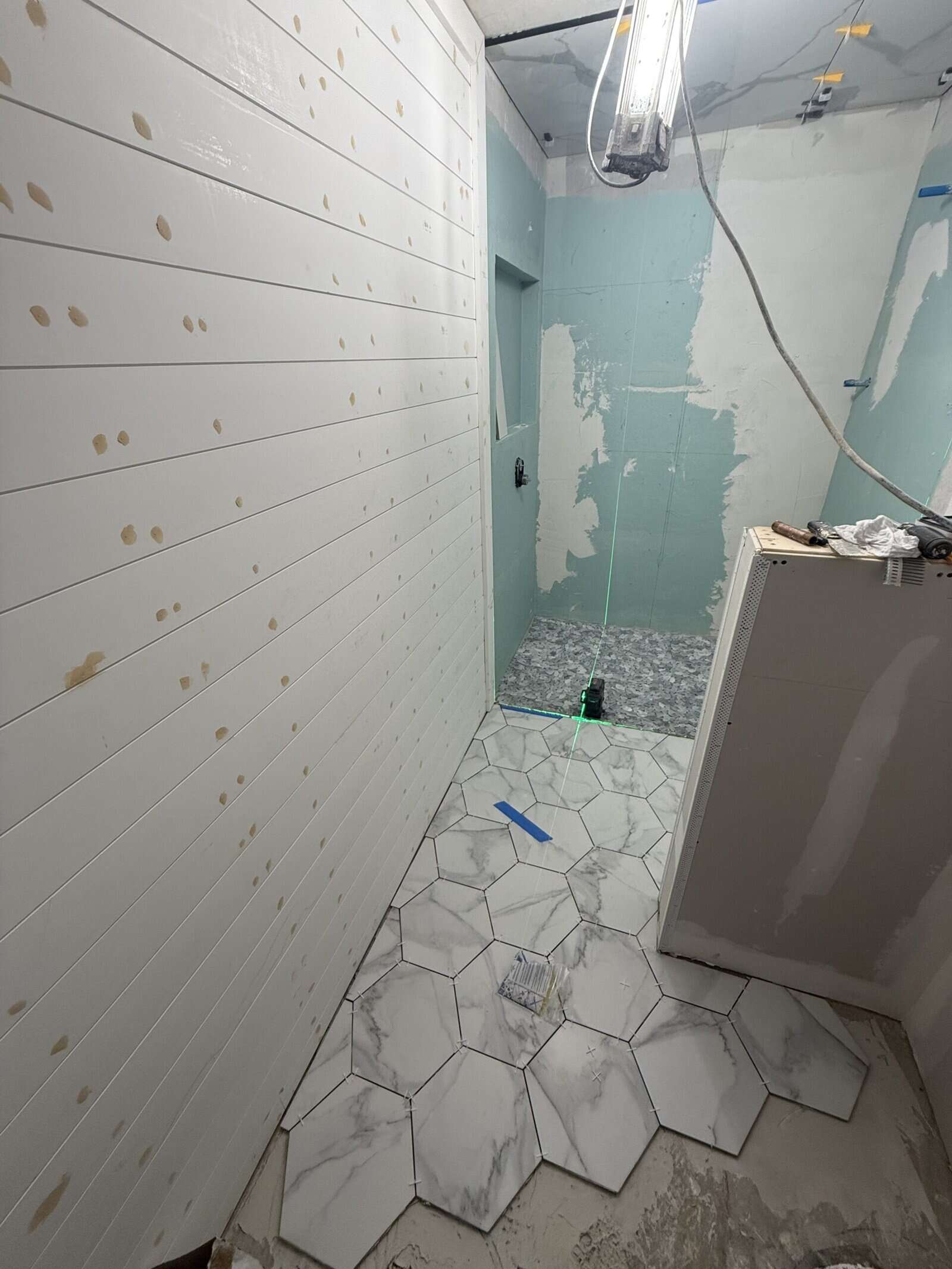 Interior bathroom remodeling with marble hex tiles and updated wall finishes.