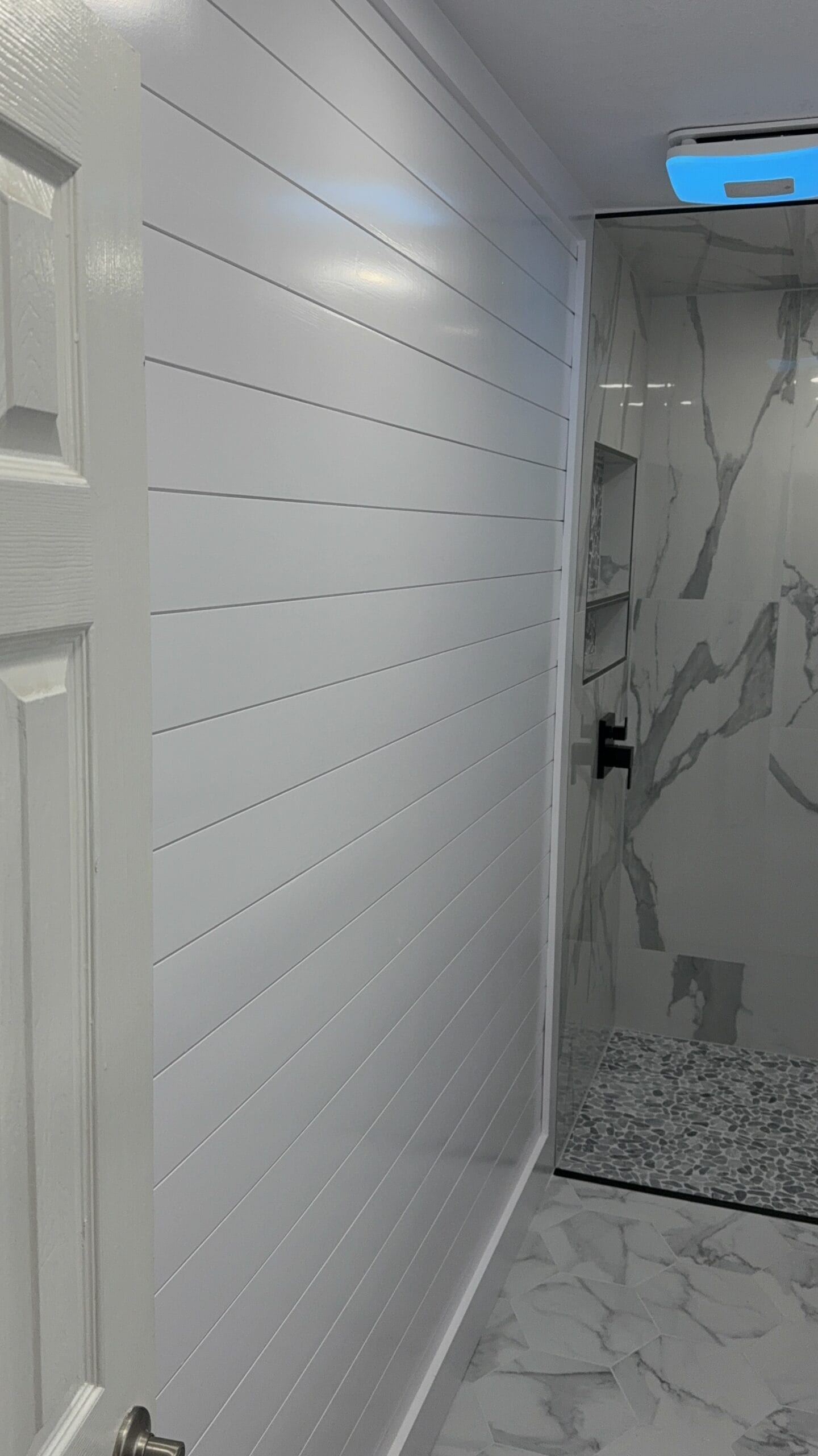 Sleek bathroom with shiplap walls and marble shower design, perfect for home remodeling.