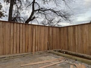 Brightly lit backyard featuring a newly built wooden privacy fence for outdoor space enhancement.