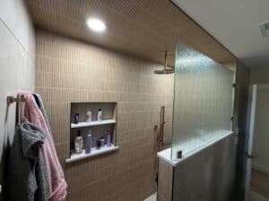 Elegant modern bathroom with beige tile walls, glass partition, and stylish shower fixtures.