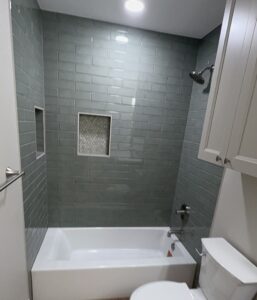 Bathroom remodel featuring stylish gray subway tiles, recessed niches, and contemporary fixtures.