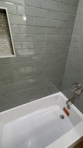 Durable gray subway tiles in bathroom with sleek bathtub and chrome fixtures.
