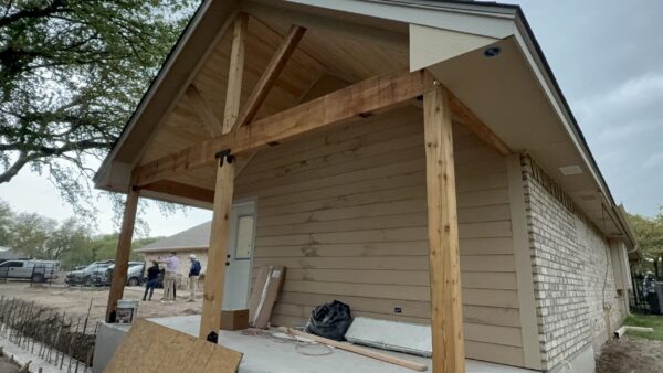 A house undergoing remodeling with new porch construction, showcasing craftsmanship and home improvement.