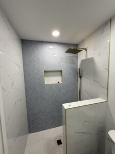 High-end bathroom renovation with elegant marble tiles and brass fixtures.