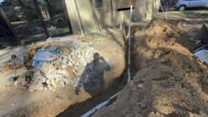 Excavation for house renovation with plumbing pipes installation and foundation work.