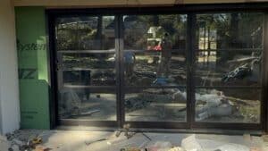 ALT text: New glass sliding doors being installed in a home renovation project.
