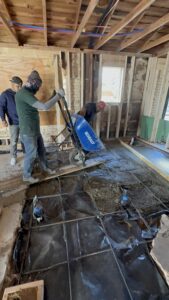 Alt text: Construction workers installing flooring and framing in a home renovation project.