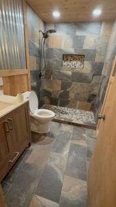 Stylish walk-in shower with natural stone tiles and built-in niche, complemented by wooden cabinetry.