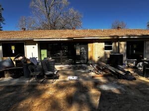 Construction site with debris, tools, and renovation materials on house backyard.