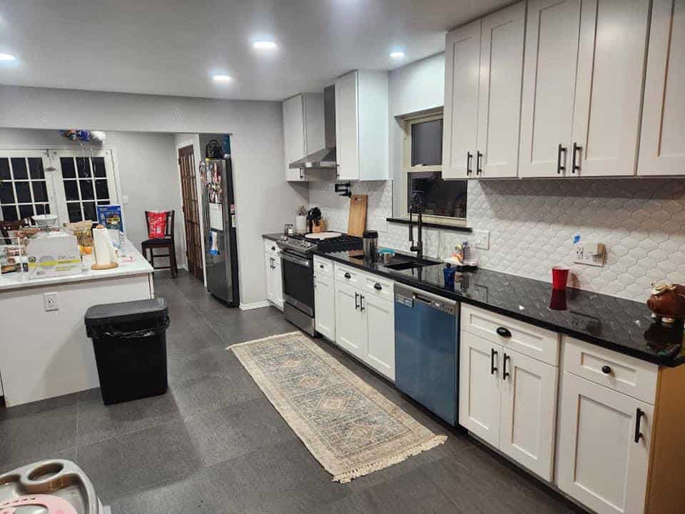 Spacious modern kitchen with white cabinets and black countertops.