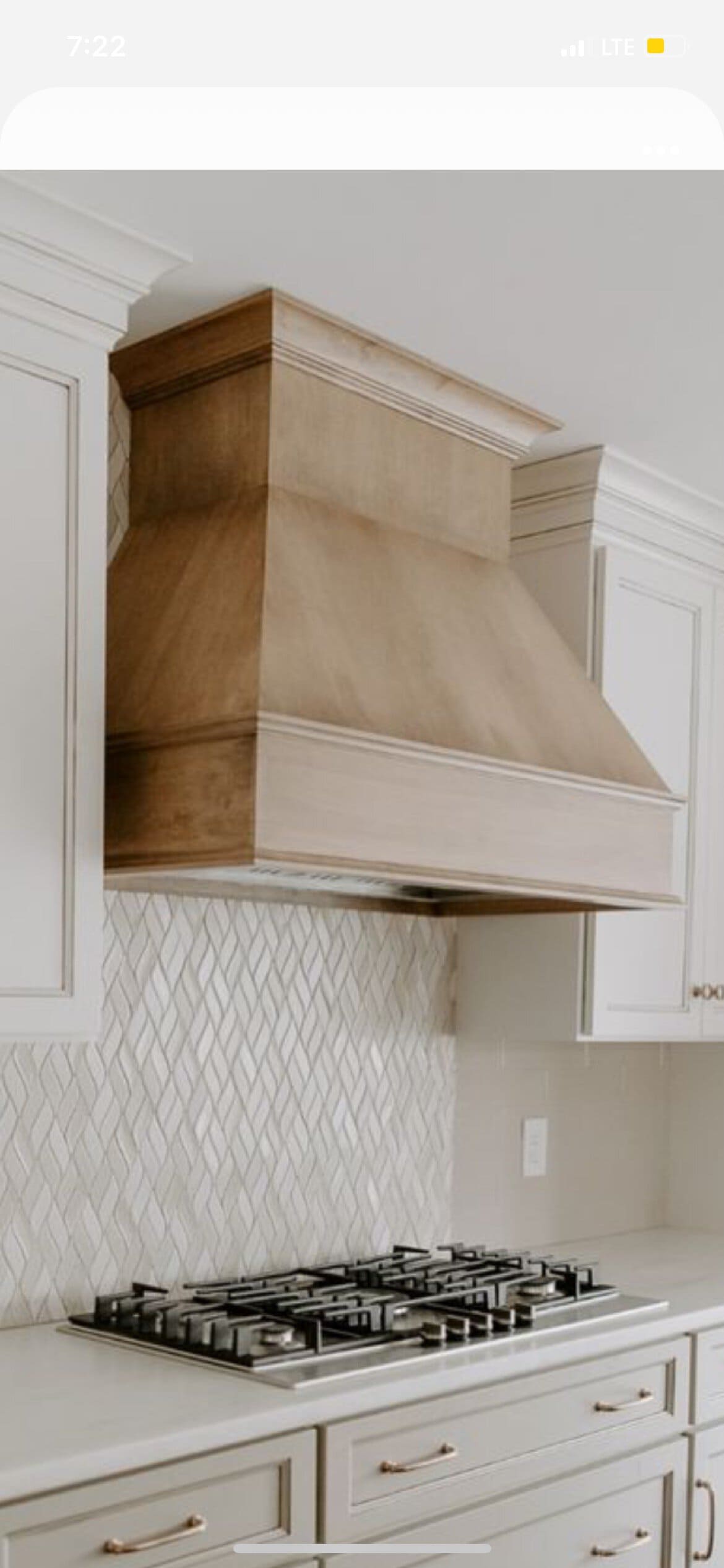 Modern kitchen with custom range hood and white cabinetry.
