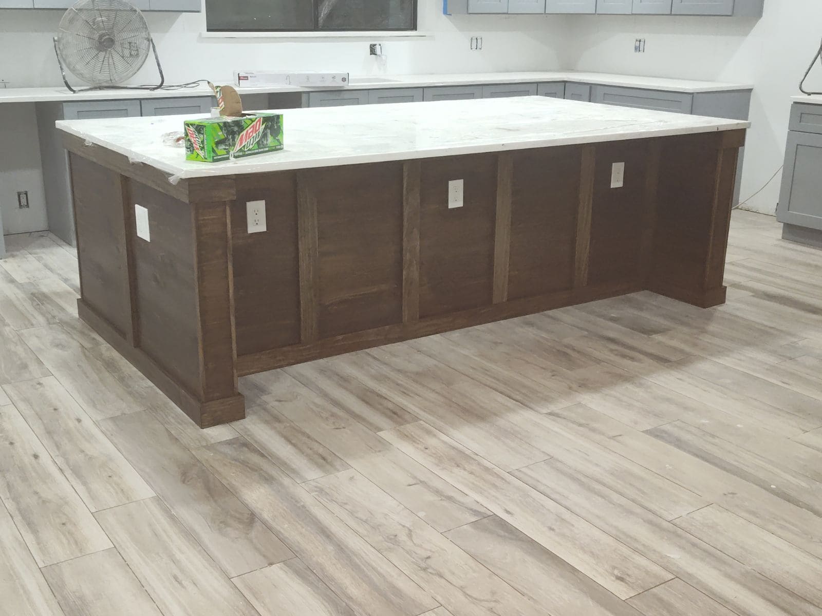 Contemporary kitchen island with marble countertop and wooden base in a bright kitchen.