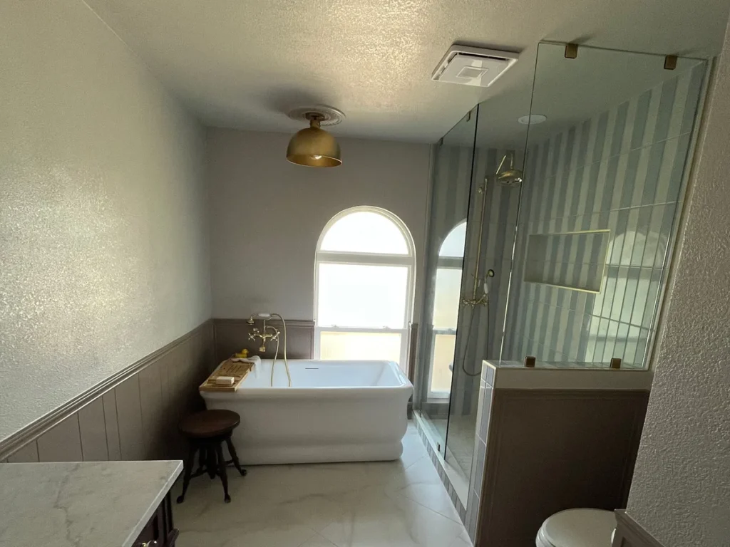Remodeled bathroom with freestanding tub, brass fixtures, and frameless glass shower — Salvation Home Remodeling