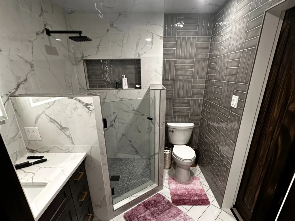 Bathroom remodel with marble-look tile, walk-in shower, and patterned accent wall by Salvation Home Remodeling