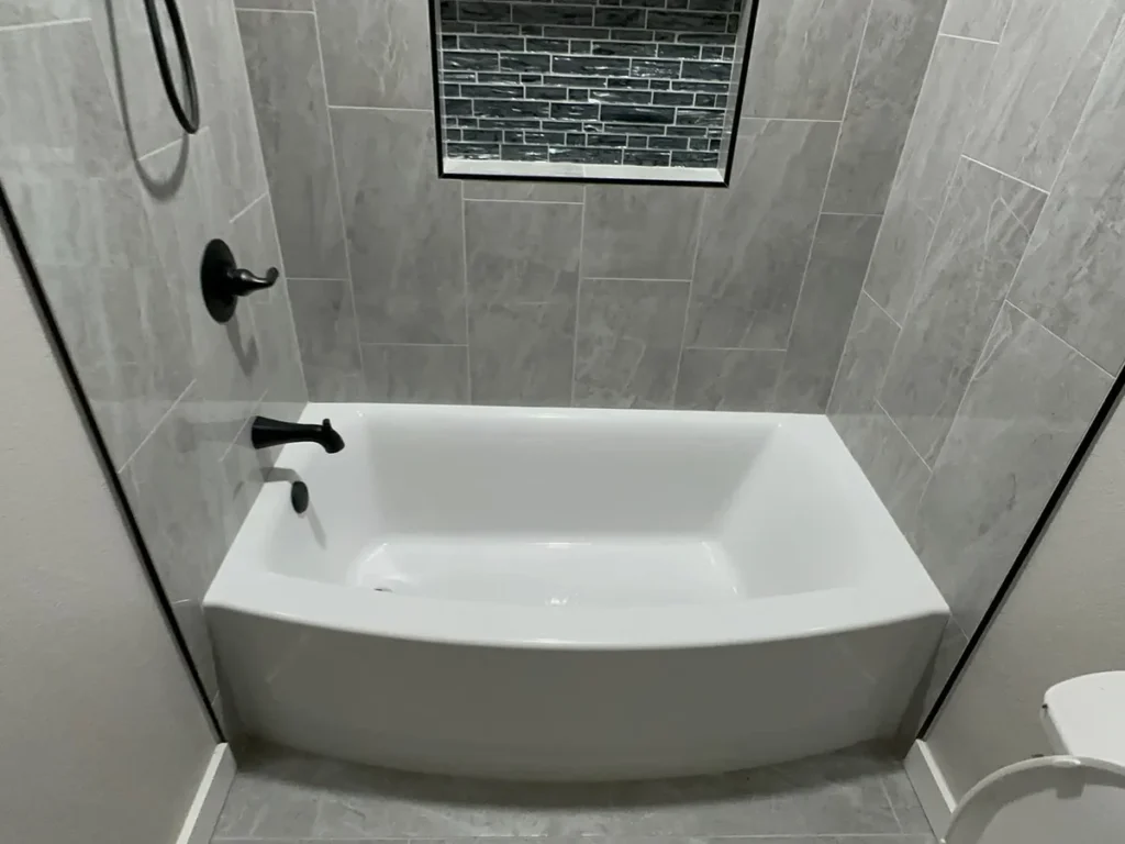 Guest bathroom remodel with new tub, tiled surround, and glass accent niche by Salvation Home Remodeling