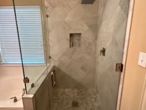 Master bathroom with tiled walk-in shower, frameless glass, and built-in tub by Salvation Home Remodeling