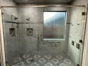 Zero-entry walk-in tile shower with dual heads, grab bar and decorative mosaic floor — Salvation Home Remodeling