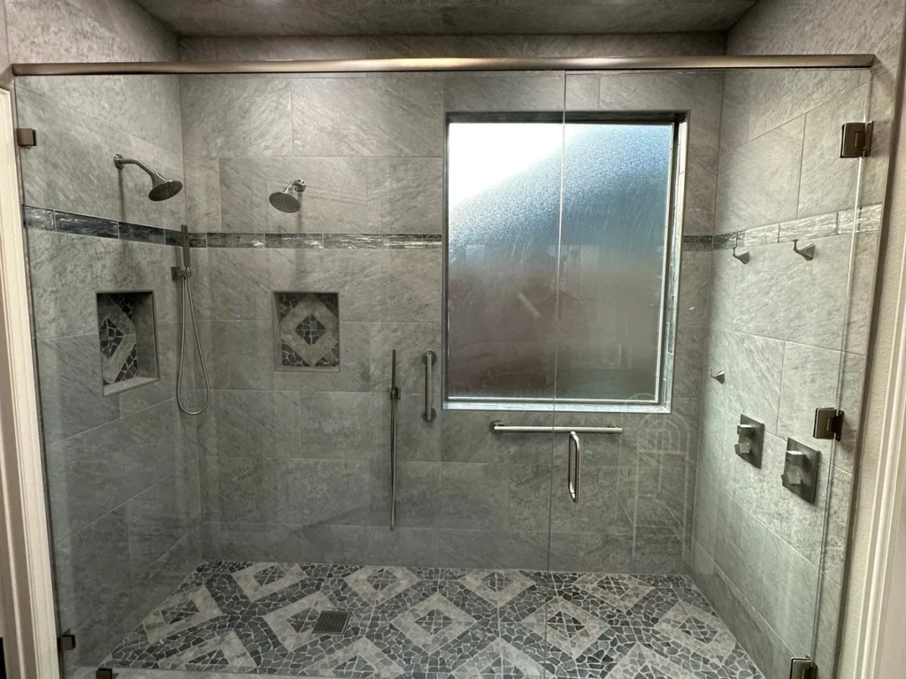 Zero-entry walk-in shower with dual shower heads, grab bars, and frameless glass by Salvation Home Remodeling