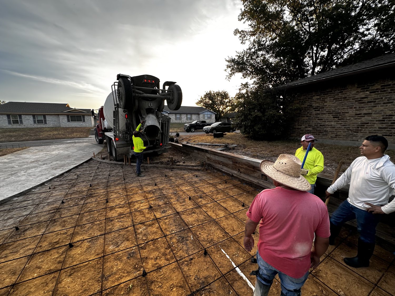 Concrete truck backed in for a driveway pour in Fort Worth, crew standing by on the tied rebar.