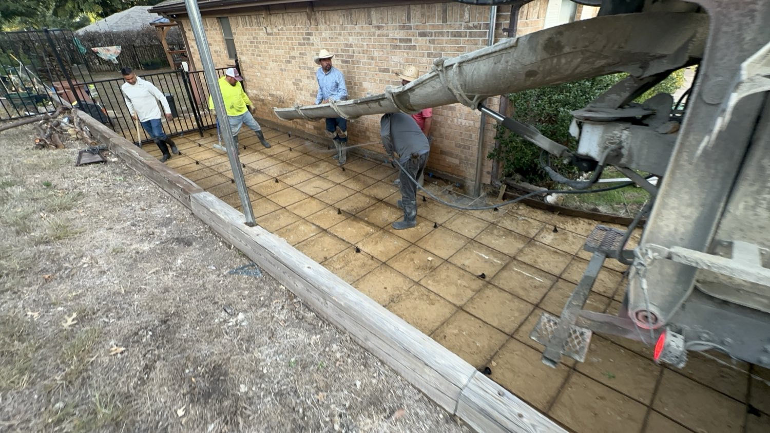 Concrete placed down the chute over reinforced rebar beside a Fort Worth brick home.
