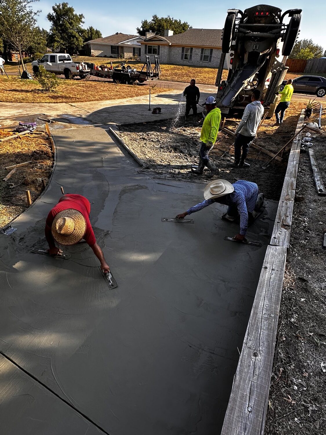 Finishers hand-troweling the curved apron of a new concrete driveway in Fort Worth.