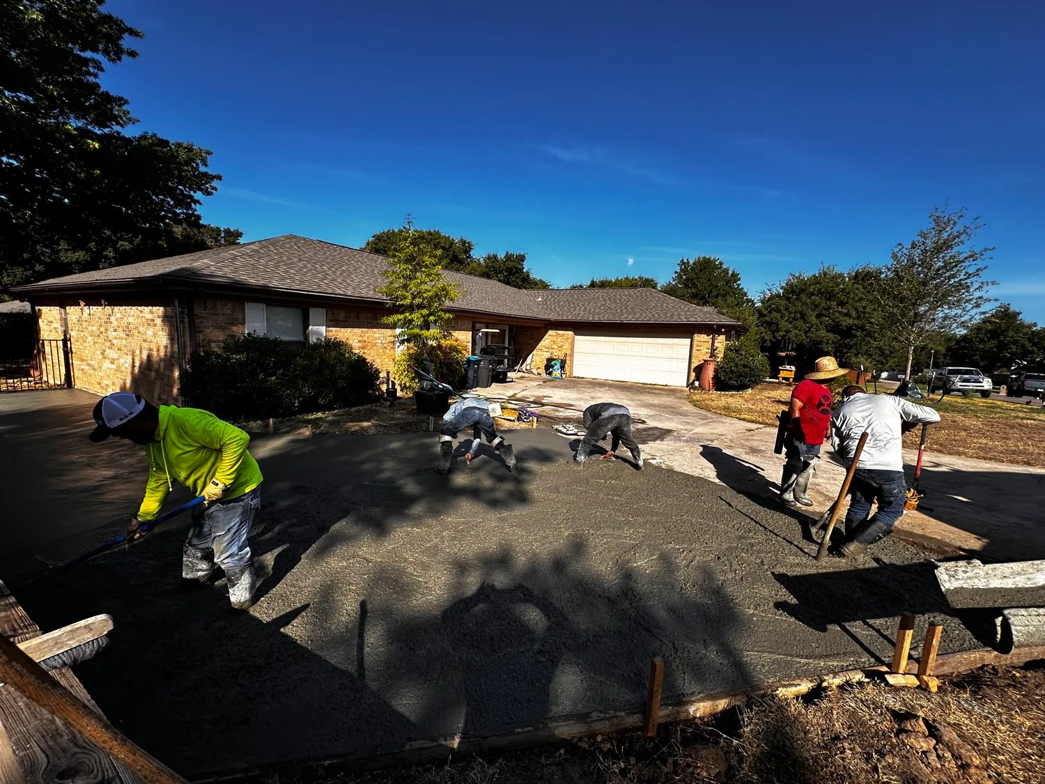 Full crew finishing a replacement concrete driveway at a Fort Worth brick ranch home.