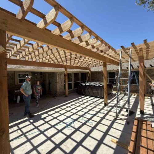 Outdoor patio covered with wooden pergola in progress by Salvation Home Remodeling.